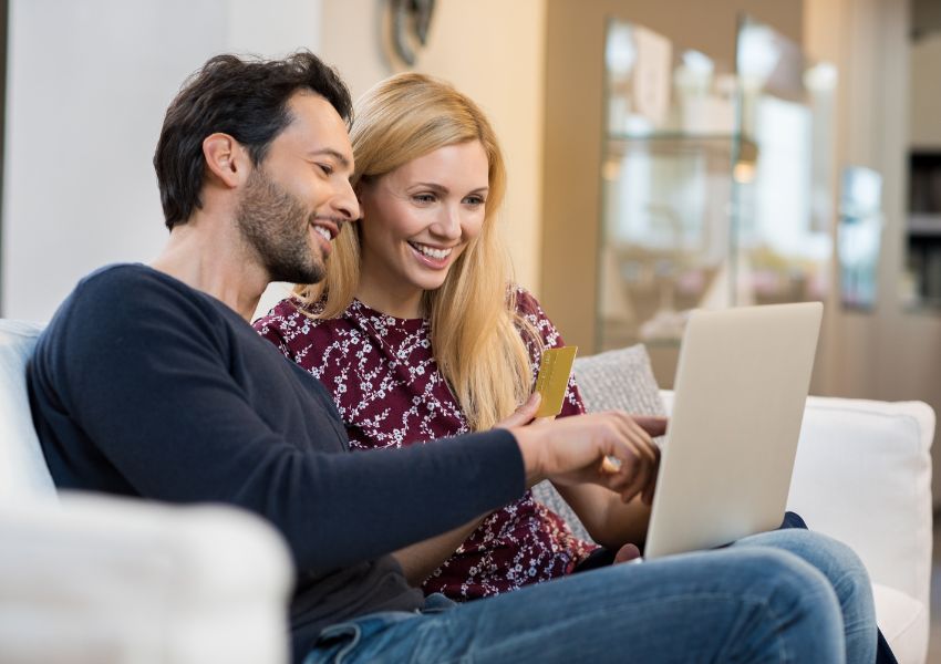 Two tenants looking at a laptop and holding a credit card to make an online payment