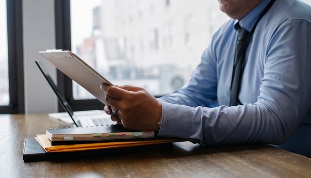 a person holding a clipboard while sitting at their desk