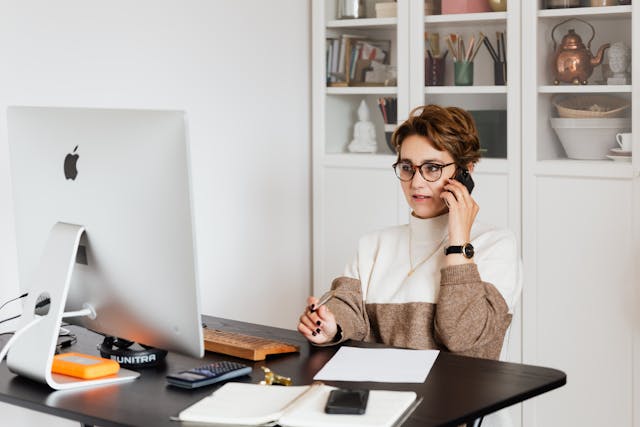 a  property manager speaking on the phone while looking at the computer